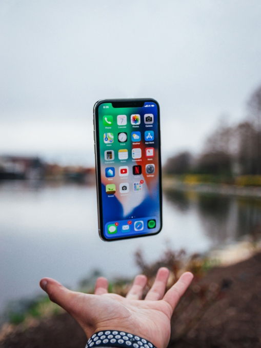silver iPhone X floating over open palm